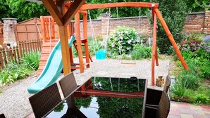 Un parque infantil con tobogán, columpios y una zona pequeña con piscina.