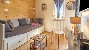 Une pièce confortable avec un canapé-lit, une petite table et une fenêtre avec des rideaux.