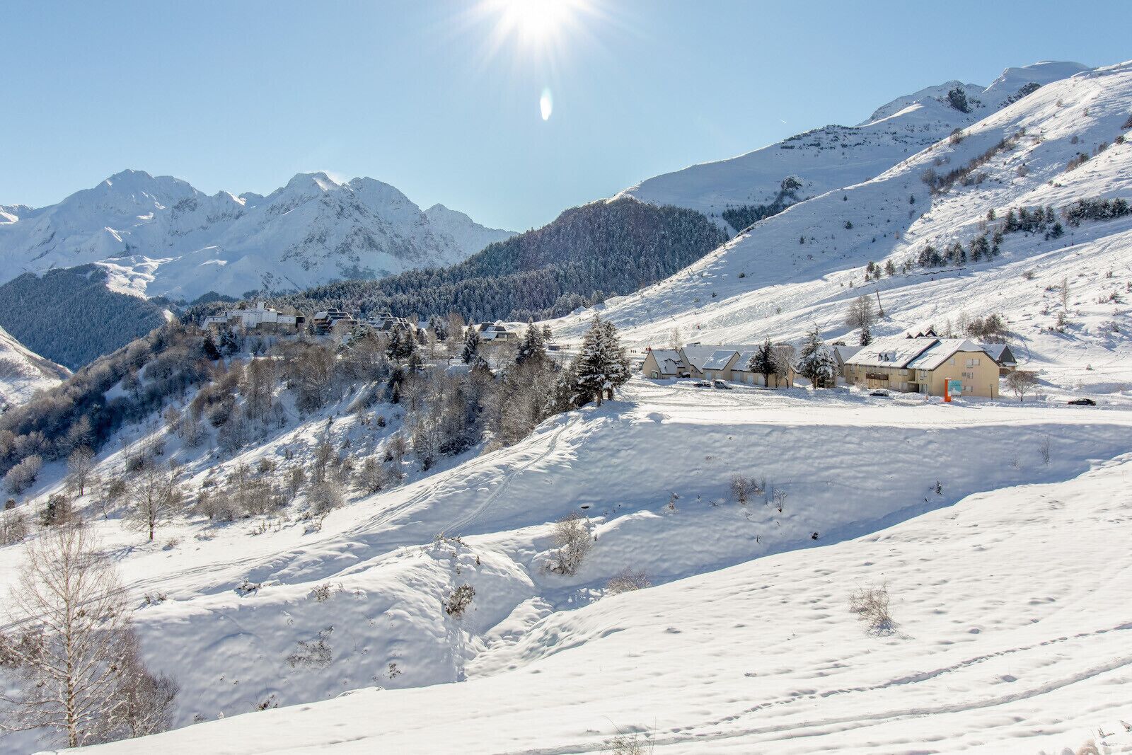 A snow-covered mountain landscape with a small cluster of buildings, likely a resort or lodge, in the foreground.