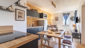 Une cuisine moderne avec des meubles en bois, une table à manger pour quatre personnes et un plan de travail noir.