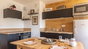 Une cuisine moderne avec des plans de travail en bois, une table à manger pour quatre personnes et un four à micro-ondes placé au-dessus de l’évier.