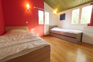 Un dormitorio con dos camas, suelo de madera y techo inclinado.