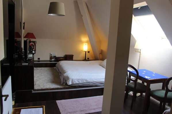 A bedroom with a bed, a desk, and a chair. There is a window providing natural light. - Chambres Privatives Chez l'Habitant (Guebwiller)