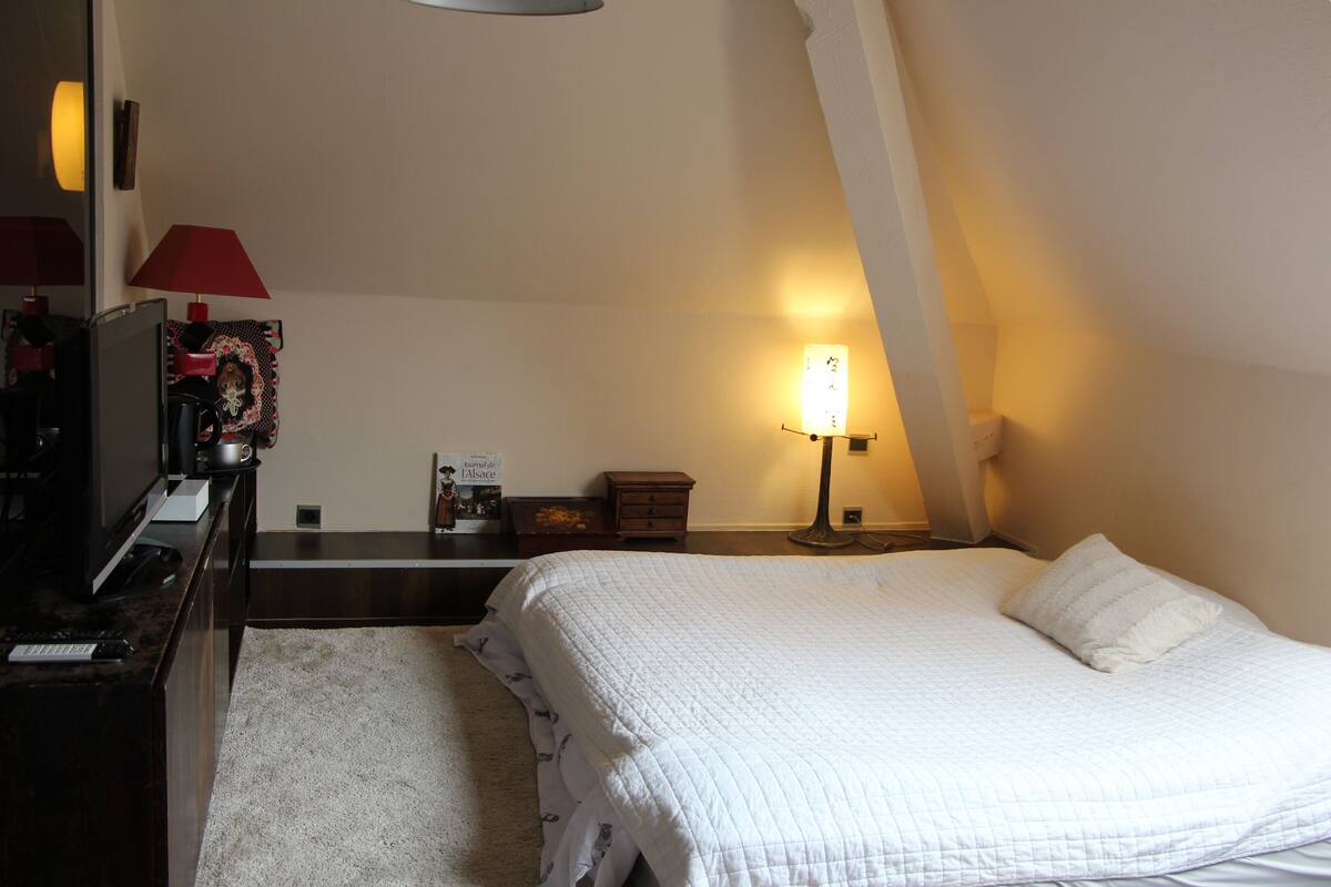 Ein Schlafzimmer mit Bett, Schreibtisch mit Lampe, Kommode und Nachttisch mit Lampe.