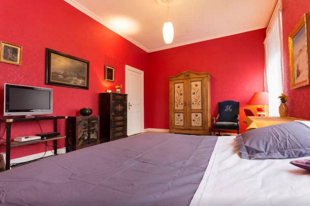 Ein Zimmer mit einem Bett, einem Fernseher, einem Kleiderschrank und einem Schreibtisch mit Stuhl.