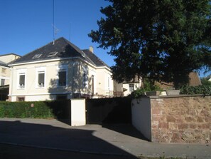 A two-story house with a sloped roof, a chimney, and a small porch. - Chambres Privatives Chez l'Habitant (Guebwiller)