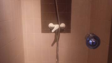 Una ducha con cabezal de ducha de mano, grifo empotrado en la pared y cabezal de ducha de mano.