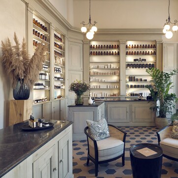A spacious room with a central island, seating area, and shelves stocked with various items.