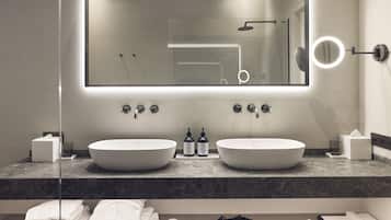 Een moderne badkamer met twee wasbakken, een grote spiegel en een badkamermeubel met toiletartikelen.