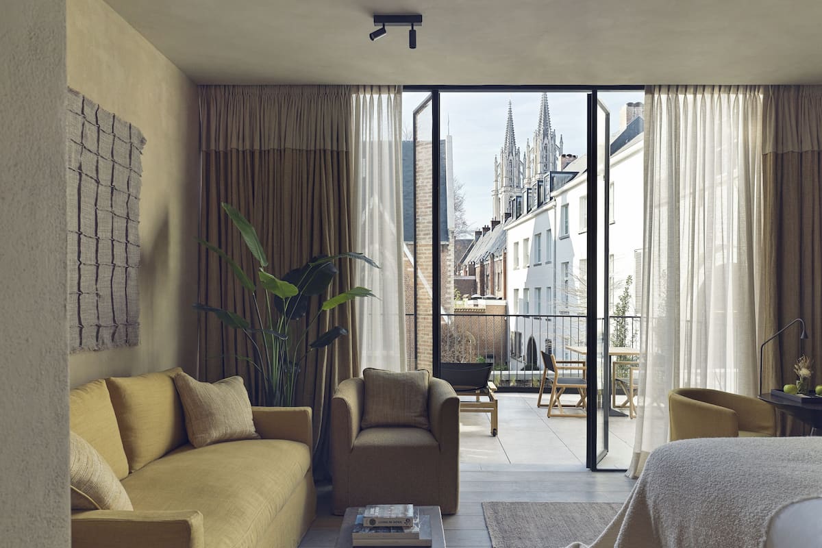 Et moderne hotelværelse med en sofa, en lænestol og et lille bord med bøger.