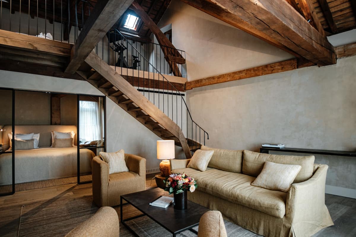 En moderne stue med sofa, sofabord og trappe med træbjælker.