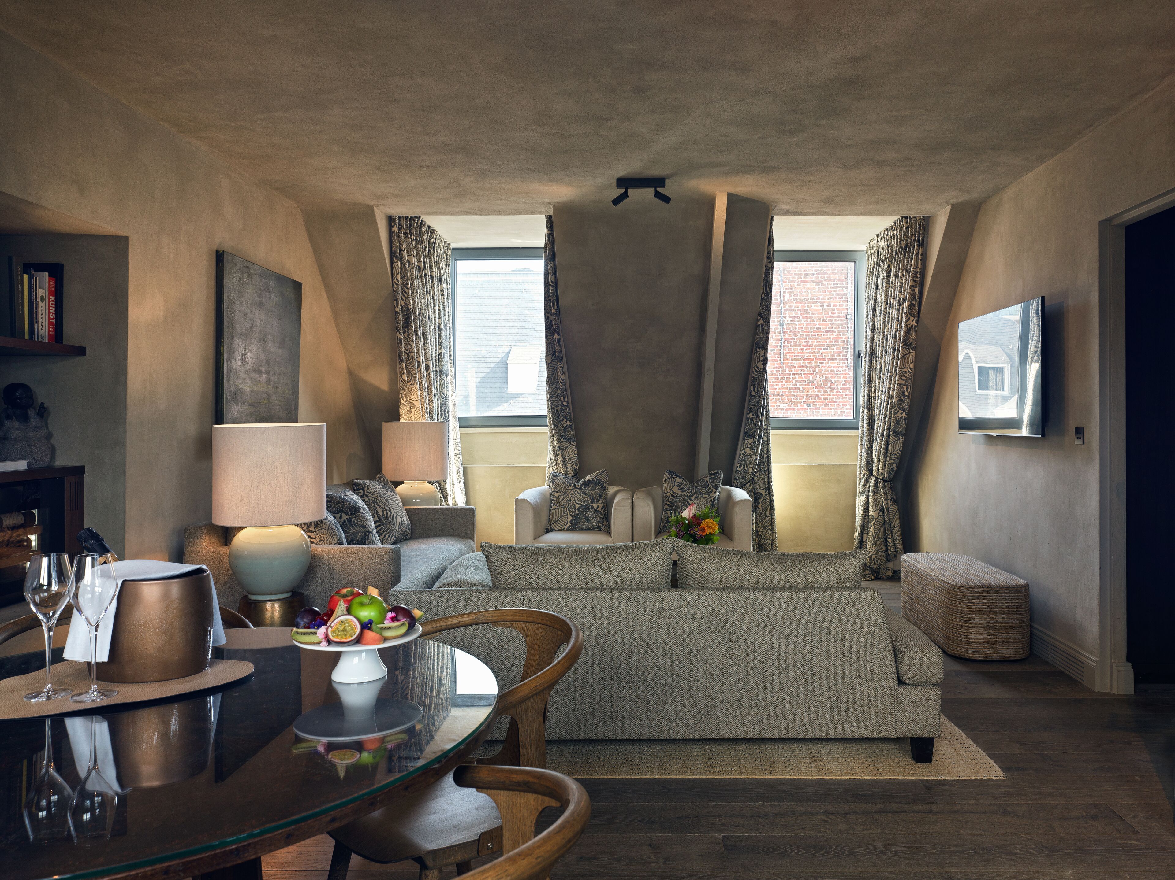 Een moderne woonkamer met een glazen eettafel, een bank en een televisie die aan de muur hangt.