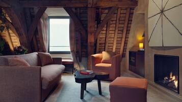 Una sala de estar estilo loft acogedora, con chimenea, vigas de madera, un sofá, un sillón y una mesita.