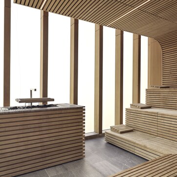 A modern interior with wooden slatted walls, a central seating area, and a small table with a chair.