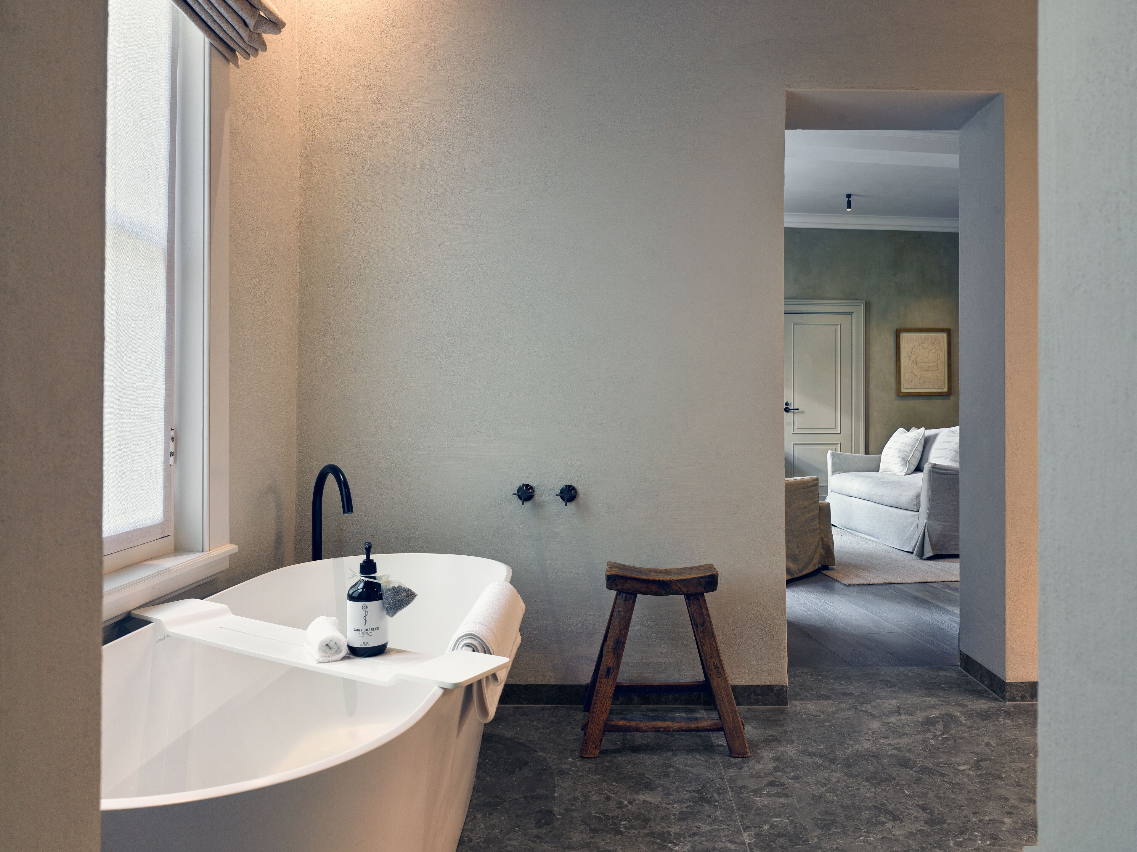 Ein modernes Badezimmer mit einer freistehenden Badewanne, einem kleinen Hocker und einem Handtuchhalter.