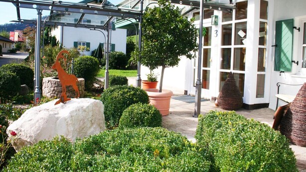 A courtyard with a glass pergola, a statue, potted plants, and a building with a green door. - Zinnkopf, Ferienwohnung , Terrasse, Küche Extra, 3 Schlaf- und 1 Wohnzimmer, max 6 Pers, Wlan (Ruhpolding)