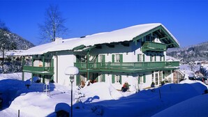 A two-story chalet with green balconies, surrounded by snow-covered mountains. - Zinnkopf, Ferienwohnung , Terrasse, Küche Extra, 3 Schlaf- und 1 Wohnzimmer, max 6 Pers, Wlan (Ruhpolding)