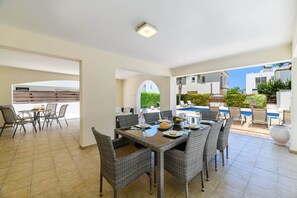 Un espace repas avec une table et des chaises, une piscine et une vue sur les bâtiments environnants.