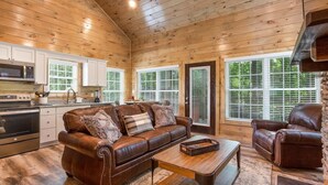 L’intérieur chaleureux d’un chalet avec un canapé en cuir, une table à manger et un coin cuisine.
