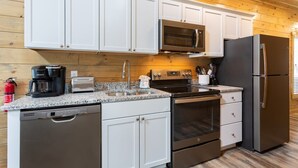 A modern kitchen with white cabinets, stainless steel appliances, a microwave, a toaster, and a coffee maker.