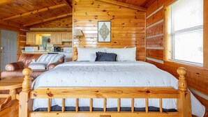 Interior de una cabaña de madera con una cama, un sofá y un comedor.