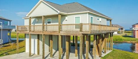 A waterfront house with a wooden deck and a covered porch.