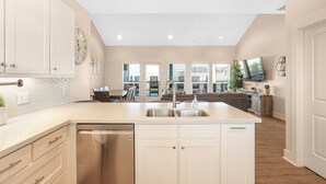 Una cocina moderna con armarios blancos, lavavajillas de acero inoxidable y una isla grande con pileta.