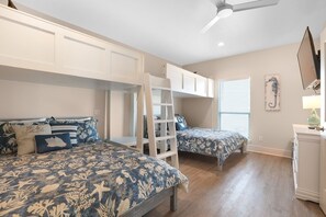 A bedroom with two beds, a ladder, and a TV.