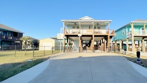 Une propriété située en bord de mer, dotée d’une allée couverte qui mène à un bâtiment comportant plusieurs balcons.