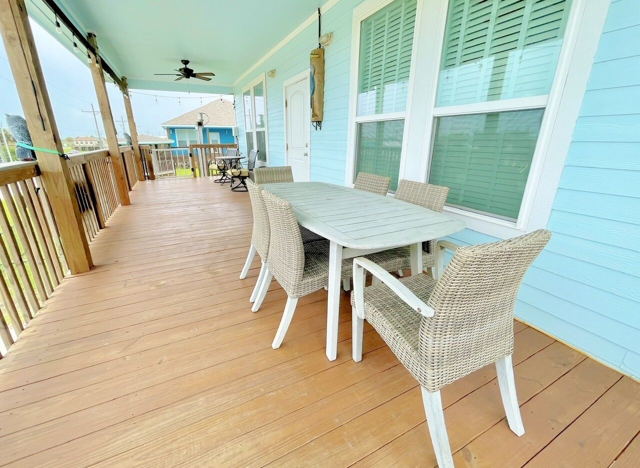 Une véranda abritée avec une table et des chaises, une terrasse en bois et une vue sur l’océan.