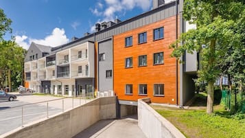 Ein modernes Mehrfamilienhaus mit mehreren Etagen, Balkonen und einem Parkplatz.