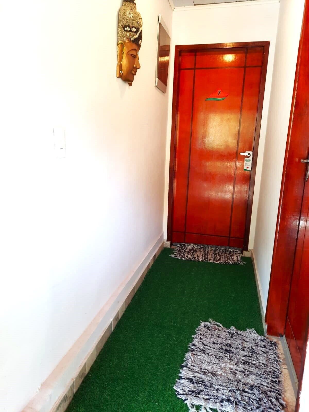 A hallway with a red door, a small rug, and a wall-mounted decorative item.