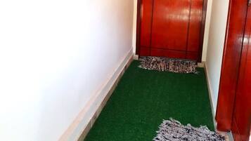A hallway with a red door, a small rug, and a wall-mounted decorative item.