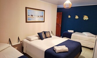 Een hotelkamer met een bed, een klein bed, een schilderij van boten aan de muur en een deur.