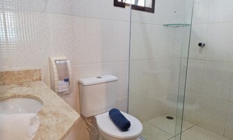 Een badkamer met toilet, handdroger, douchecabine van glas en een marmeren aanrechtblad.