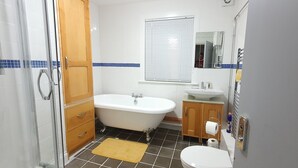 Een badkamer met een bad, toilet, wastafel en houten kastjes.