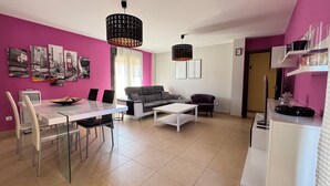A modern living room with a dining area, featuring a sofa, coffee table, and a dining table with chairs. - Luxury apartment in Residencial El Mocan (Palm-Mar)