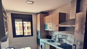 A compact kitchen with a washing machine, microwave, and stainless steel refrigerator. - Luxury apartment in Residencial El Mocan (Palm-Mar)