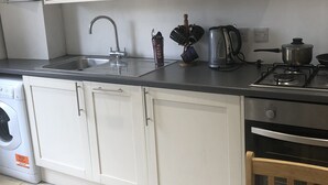 A kitchen with white cabinets, a stainless steel sink, a coffee maker, and a stove.