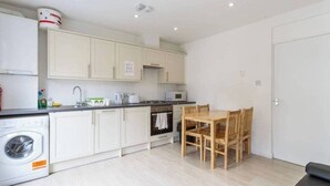 A compact kitchen with white cabinets, a microwave, a sink, and a wooden dining table.