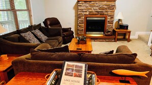 A cozy living room with a stone fireplace, leather sofas, and a wooden coffee table.