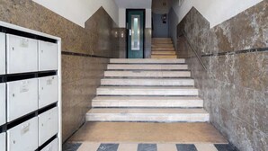 Eine Treppe mit Metallgeländer führt zu einer Tür mit grünem Rahmen.