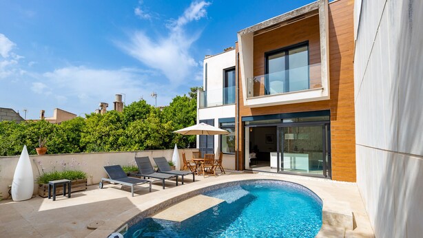 Ein modernes, zweistöckiges Haus mit Swimmingpool, Sitzgelegenheiten im Freien und einem gepflegten Garten.