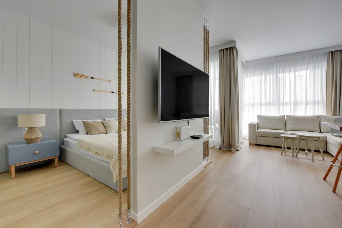 A modern bedroom with a bed, bedside table, TV, and a seating area with a sofa and coffee table.