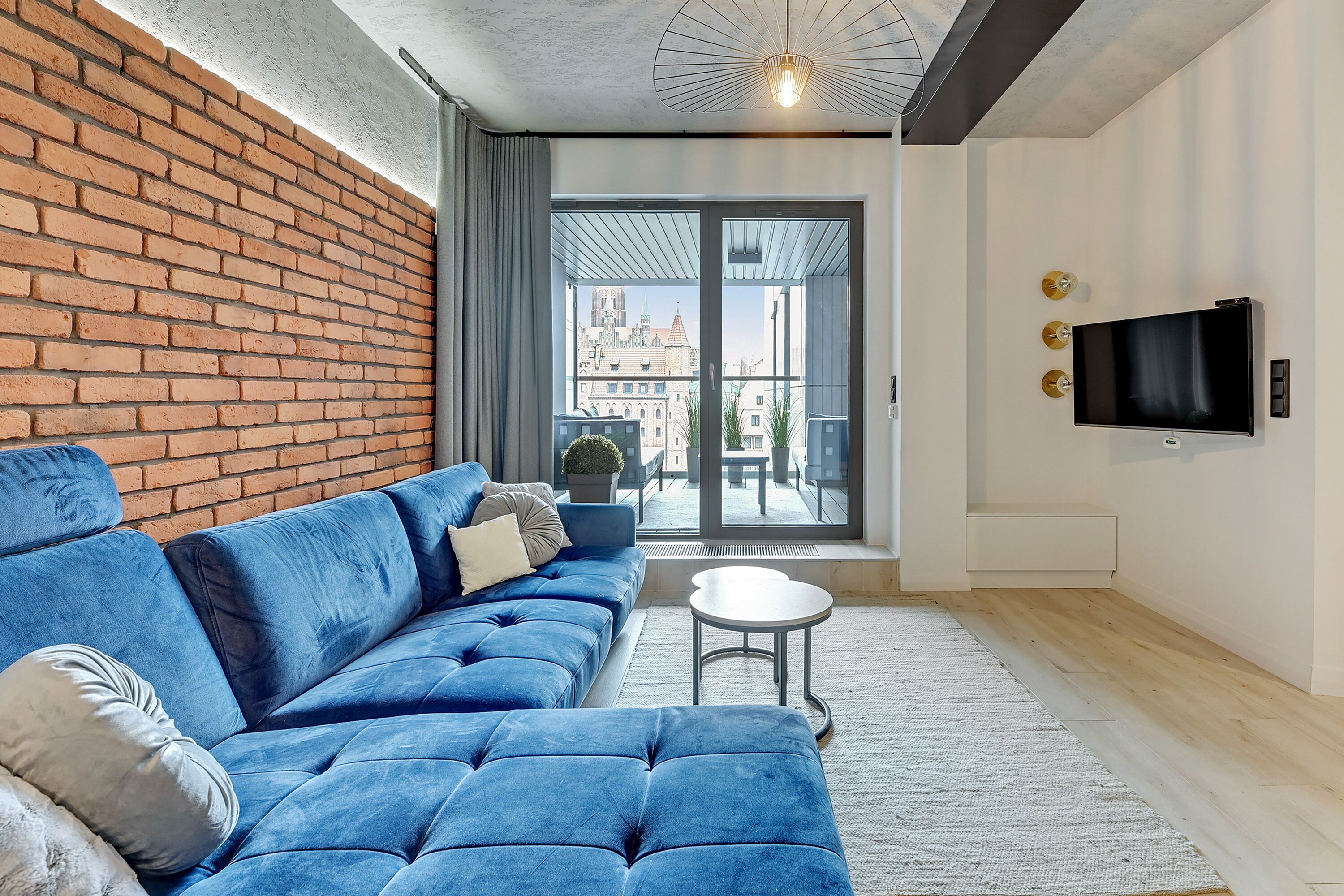 A modern living room with a blue sofa, a small round table, and a TV mounted on the wall.