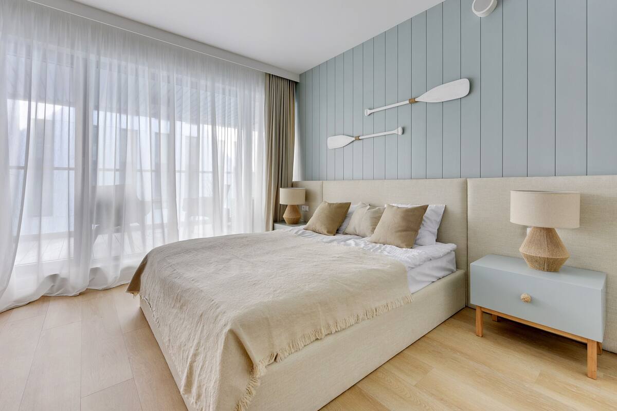 A bedroom with a large bed, a nightstand with a lamp, and a wall-mounted paddleboard decoration.