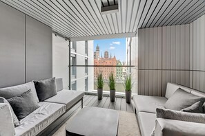 A modern balcony with a view of a historic building, grey sofas, and potted plants. - Comfort Apartments Granaria (Gdansk)
