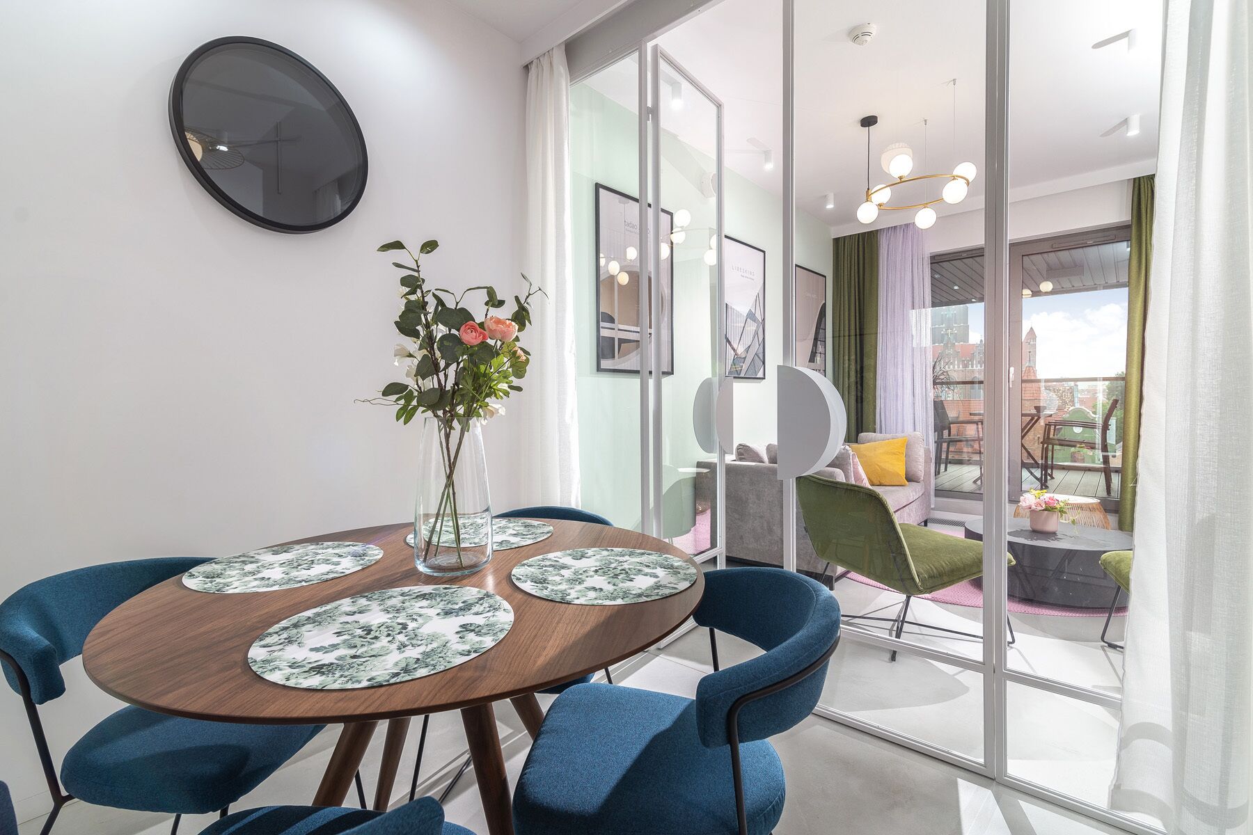 Un área de comedor moderna con una mesa redonda, sillas azules y un jarrón con flores.