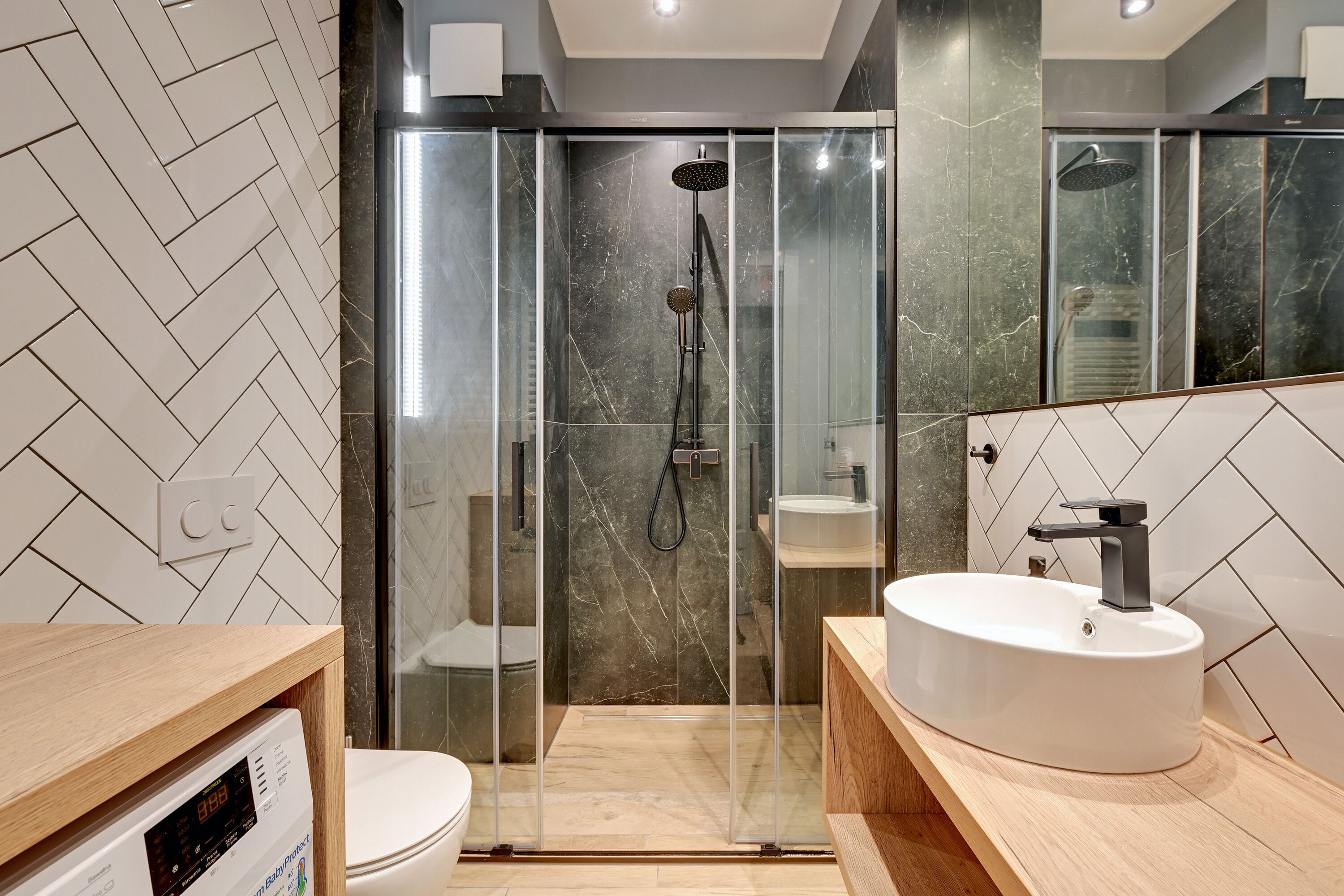 A modern bathroom with a glass-enclosed shower, a white sink, and a toilet.