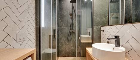 A modern bathroom with a glass-enclosed shower, a white sink, and a toilet.